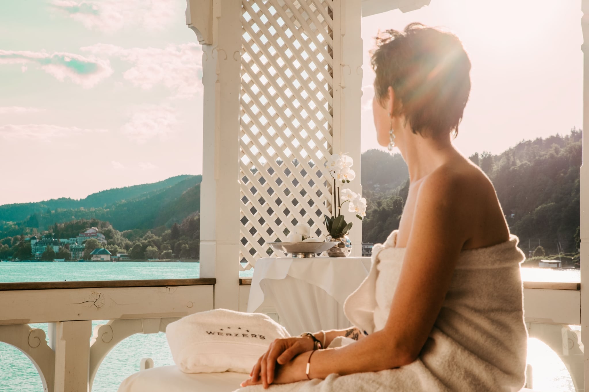 Frau beim Entspannen nach der Massage auf der Badehaus-Terrasse mit Blick auf den Wörthersee.